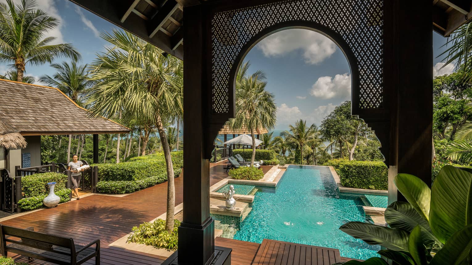 View from arched pergola to long outdoor swimming pool, sunny deck