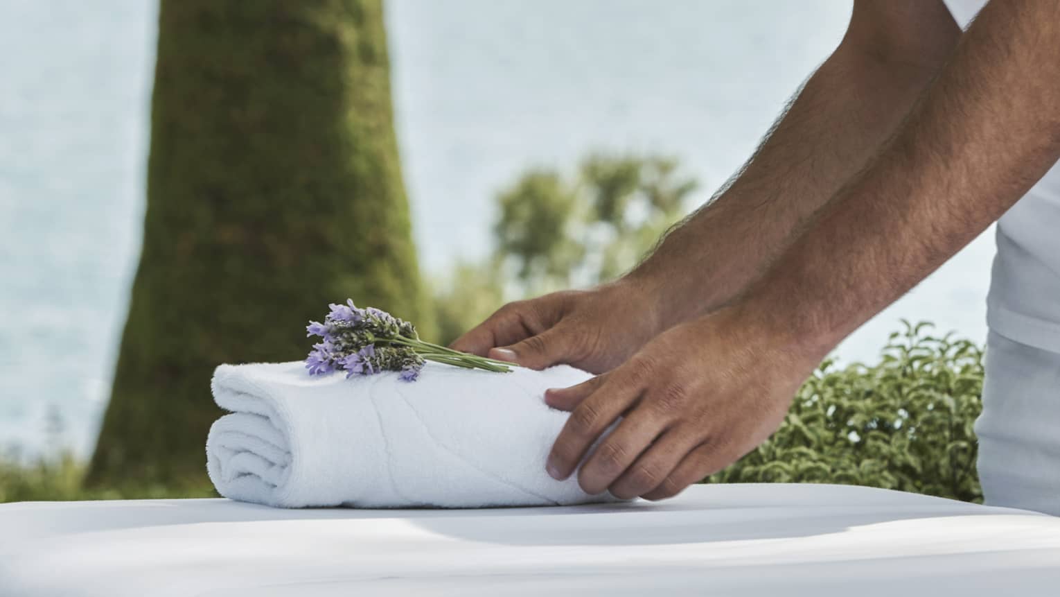 Close-up of hands setting on folded white towel with lavender sprig