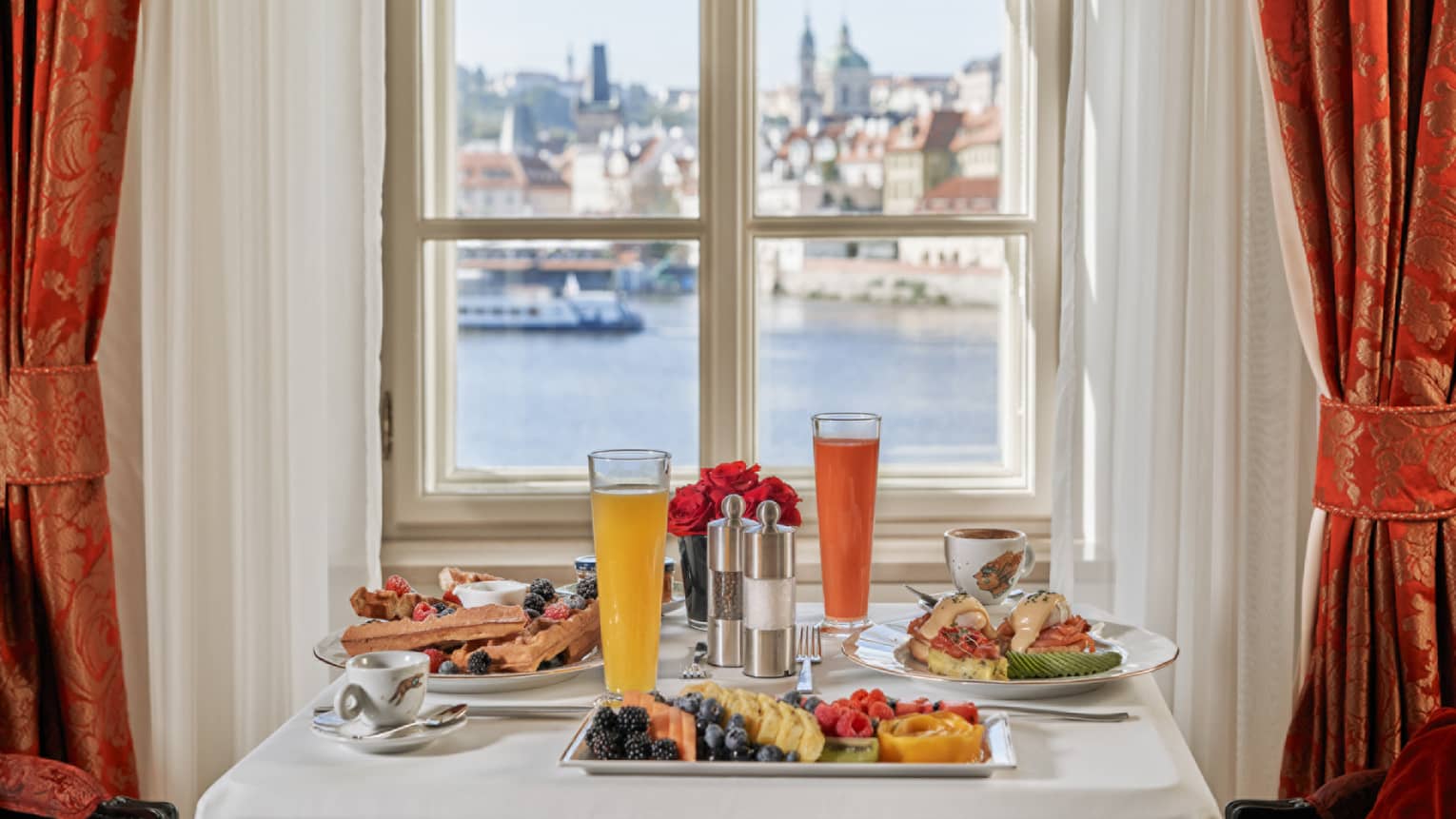 Table set for two with breakfast, window looks out to river and Prague Castle
