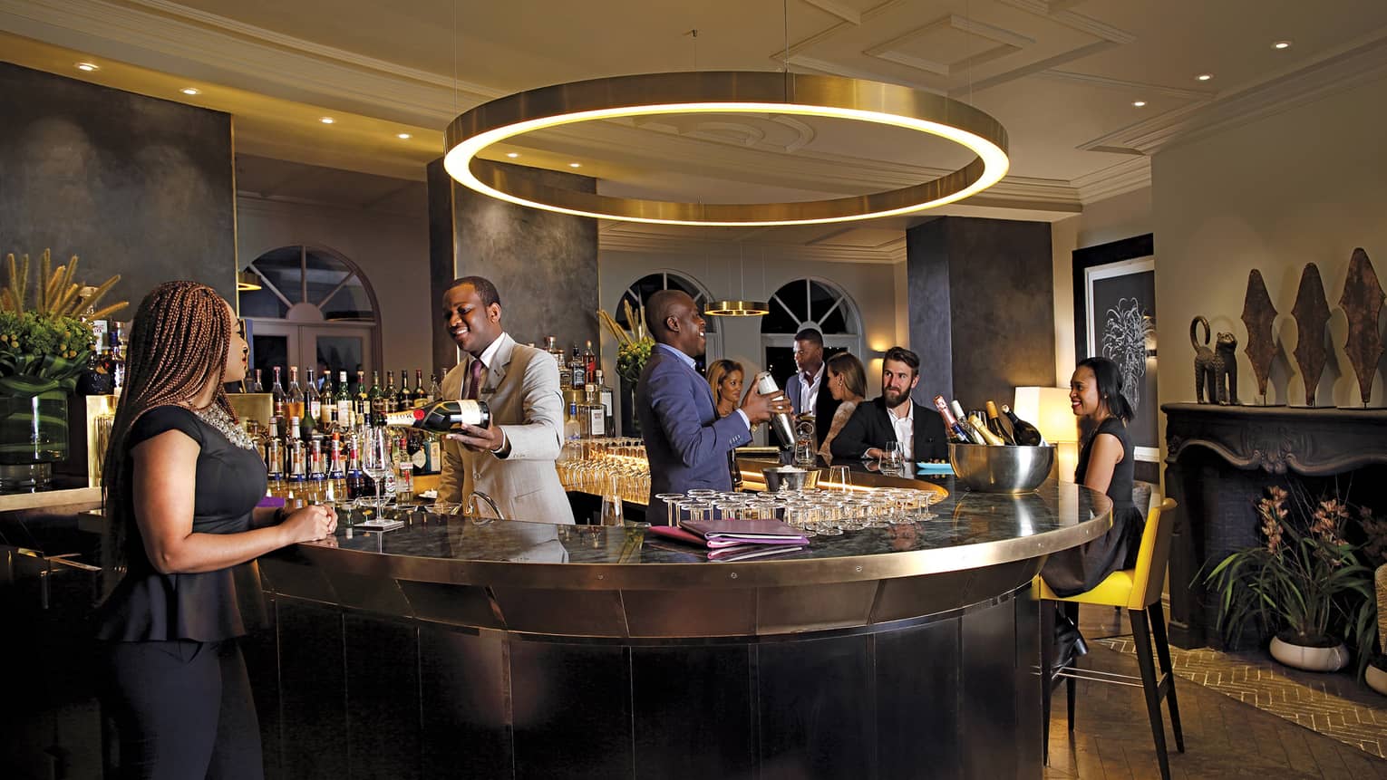 Guests around small circular bar where two bartenders pour drinks