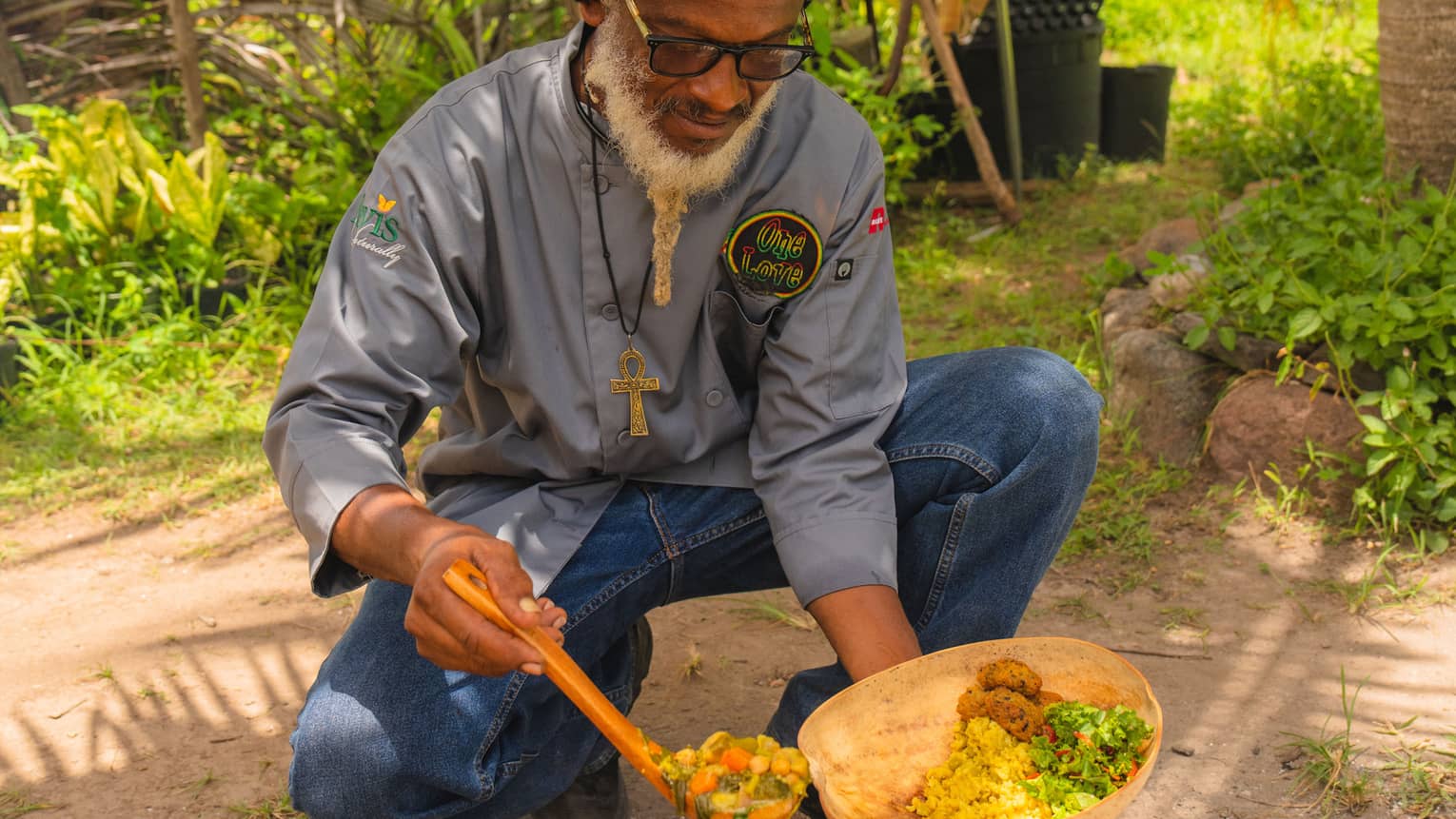 A man cooking outside amongst palm trees.