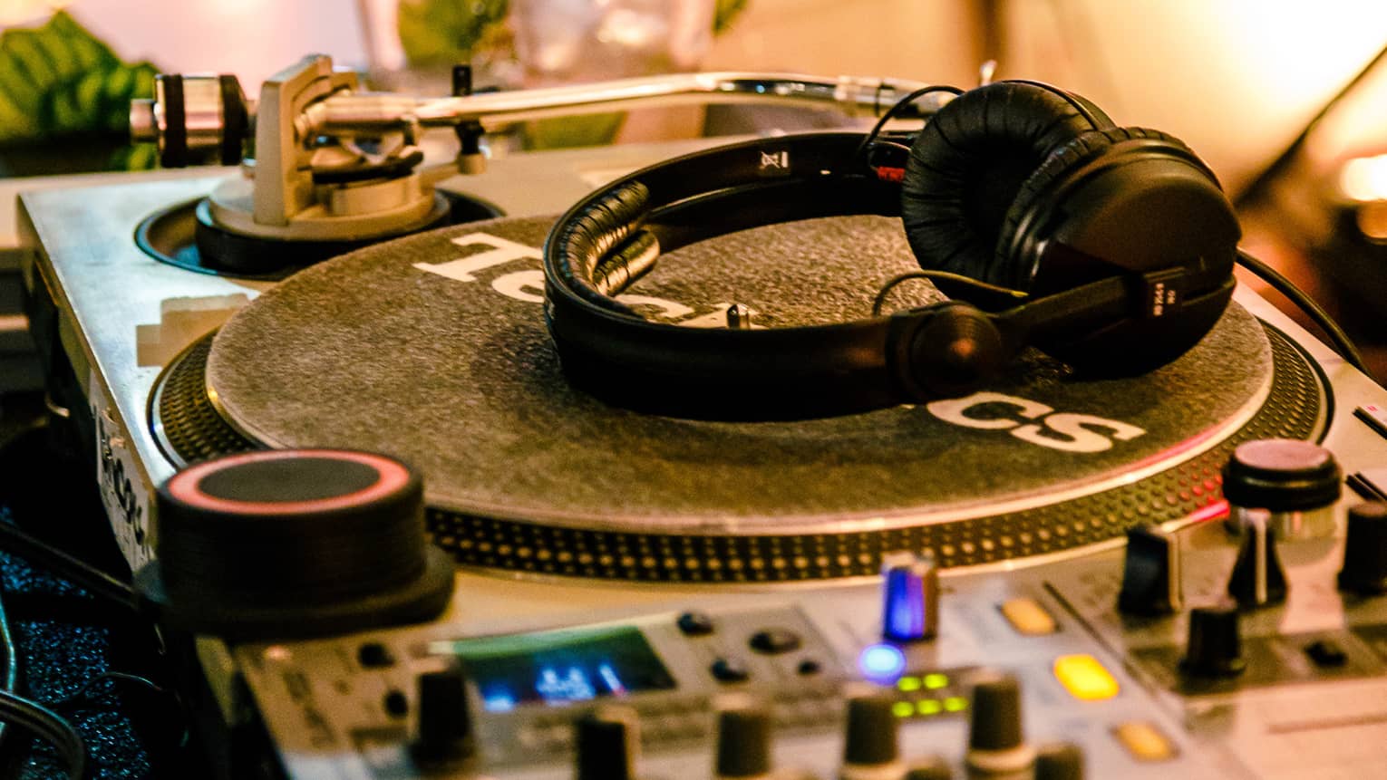 Headphones rest on turntable in DJ booth station