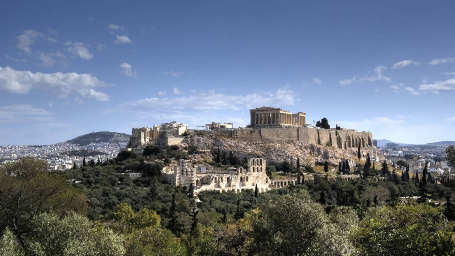 Ancient ruins of Acropolis on mountain surrounded by greenery 