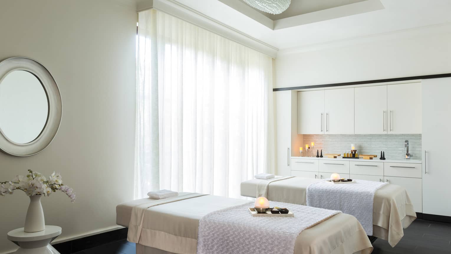 Couples Suite two massage tables with trays with glowing candles, salts in spa treatment room