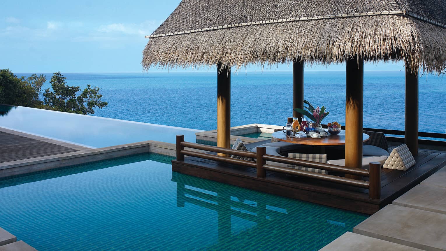 Infinity pool overlooking the Gulf of Thailand with a thatched-roof cabana