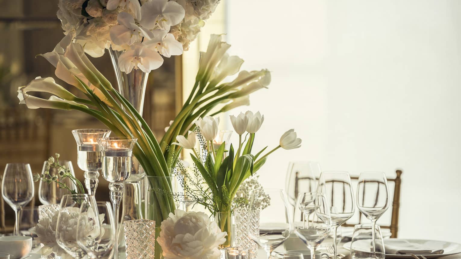 Western Banquet room dining table with glassware, long stemmed white flowers in vase