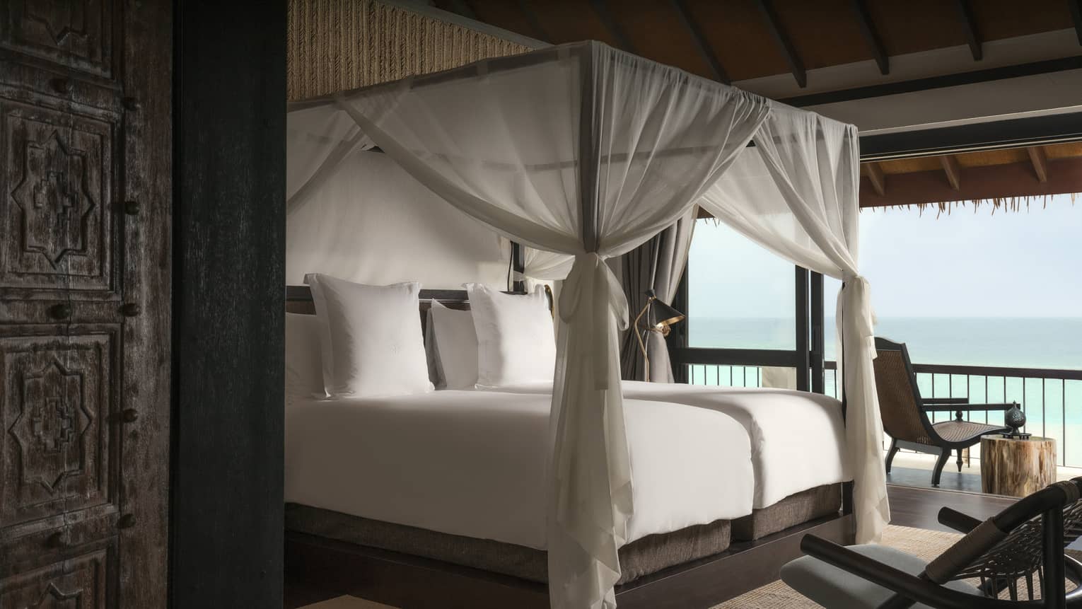 Villa poster bed with white canopy by open wall with ocean views