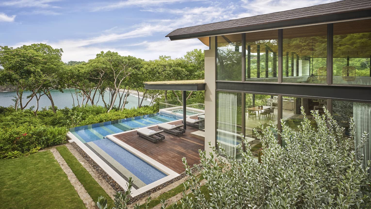 Exterior view of a Costa Rican villa with l-shaped pool and wooden deck
