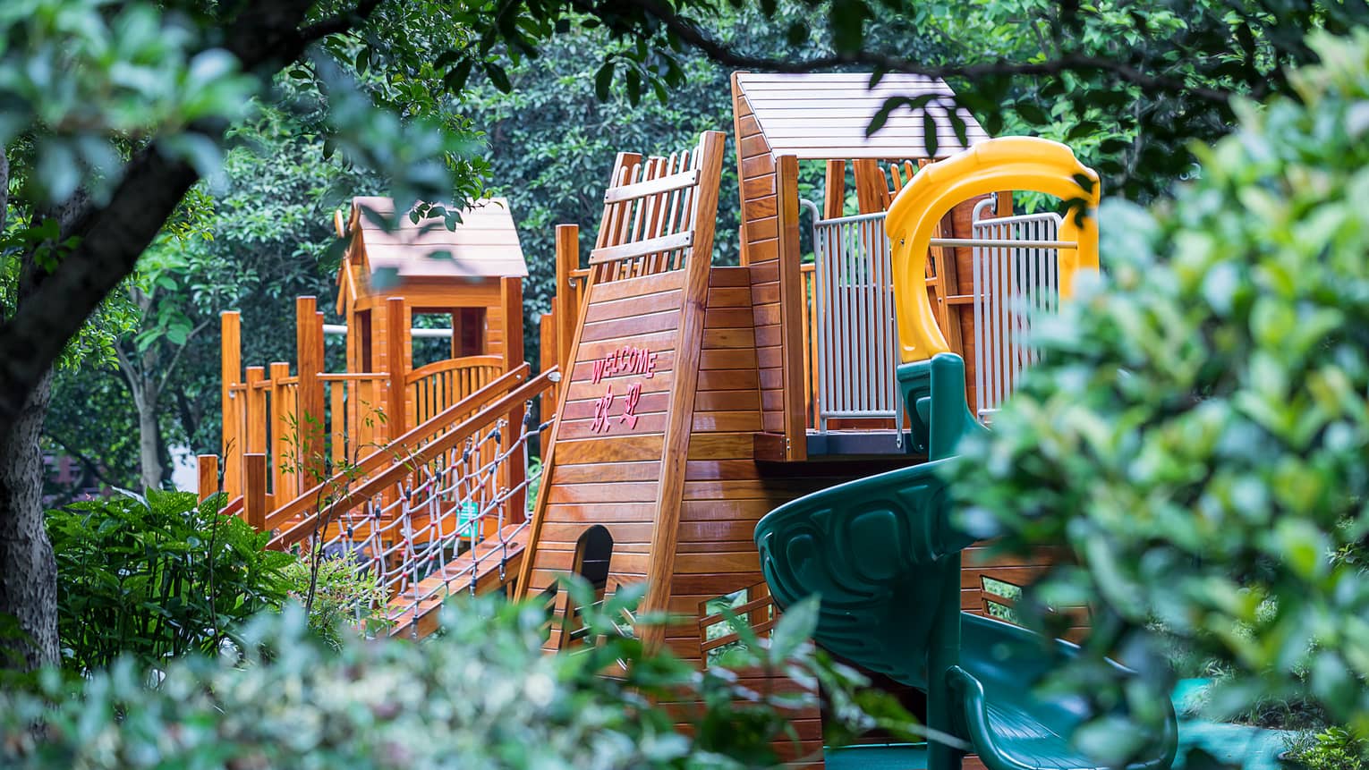 Outdoor wood playground, spiral plastic slide between trees