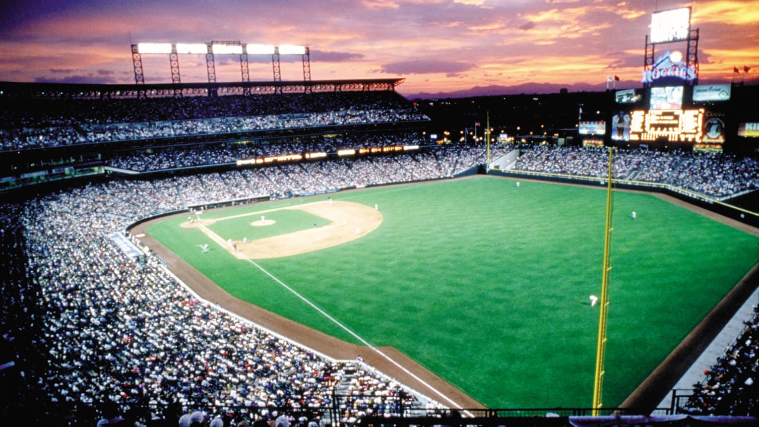 Aerial view of Coors Field sports stadium at sunset, crowds in stands