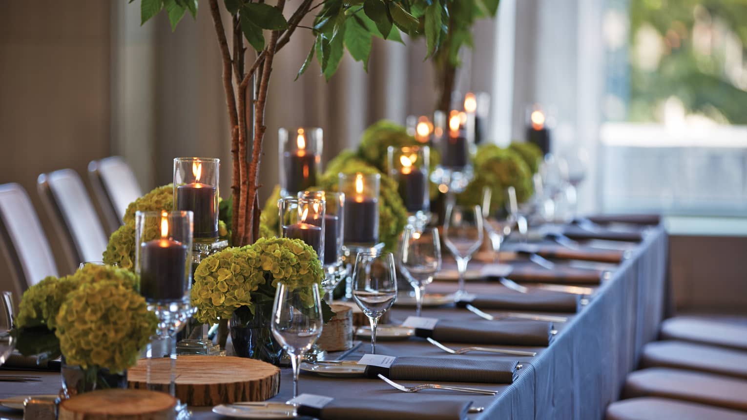 Black pillar candles in votives, green flowers, wine glasses along banquet table