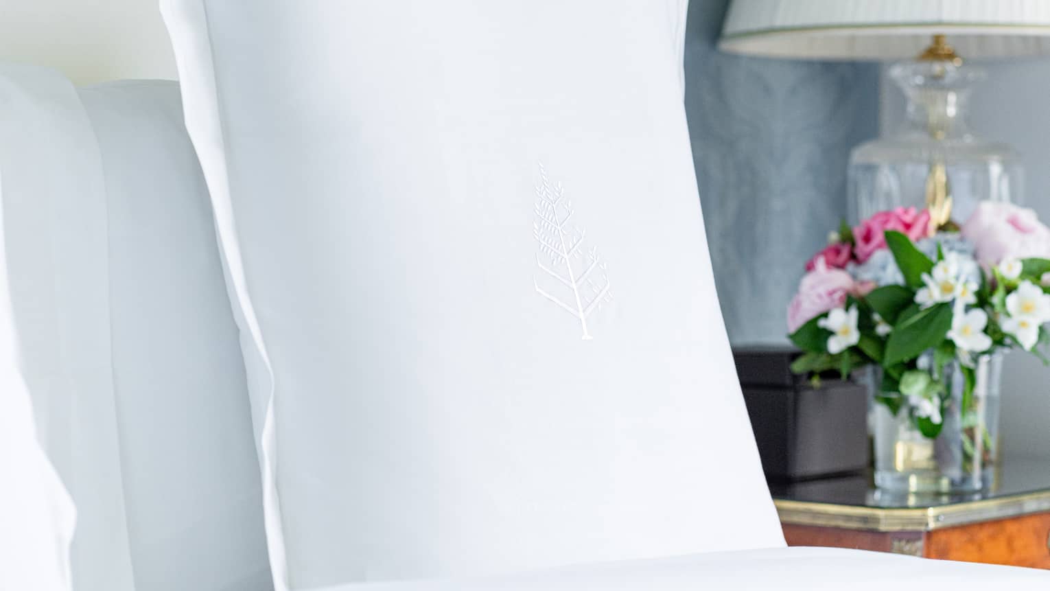 Close-up of a bed pillow with Four Seasons logo on it, in a luxury hotel suite