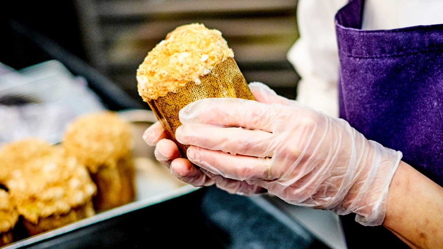 Close-up of chef pastry wearing gloves, holding rolled baked goods