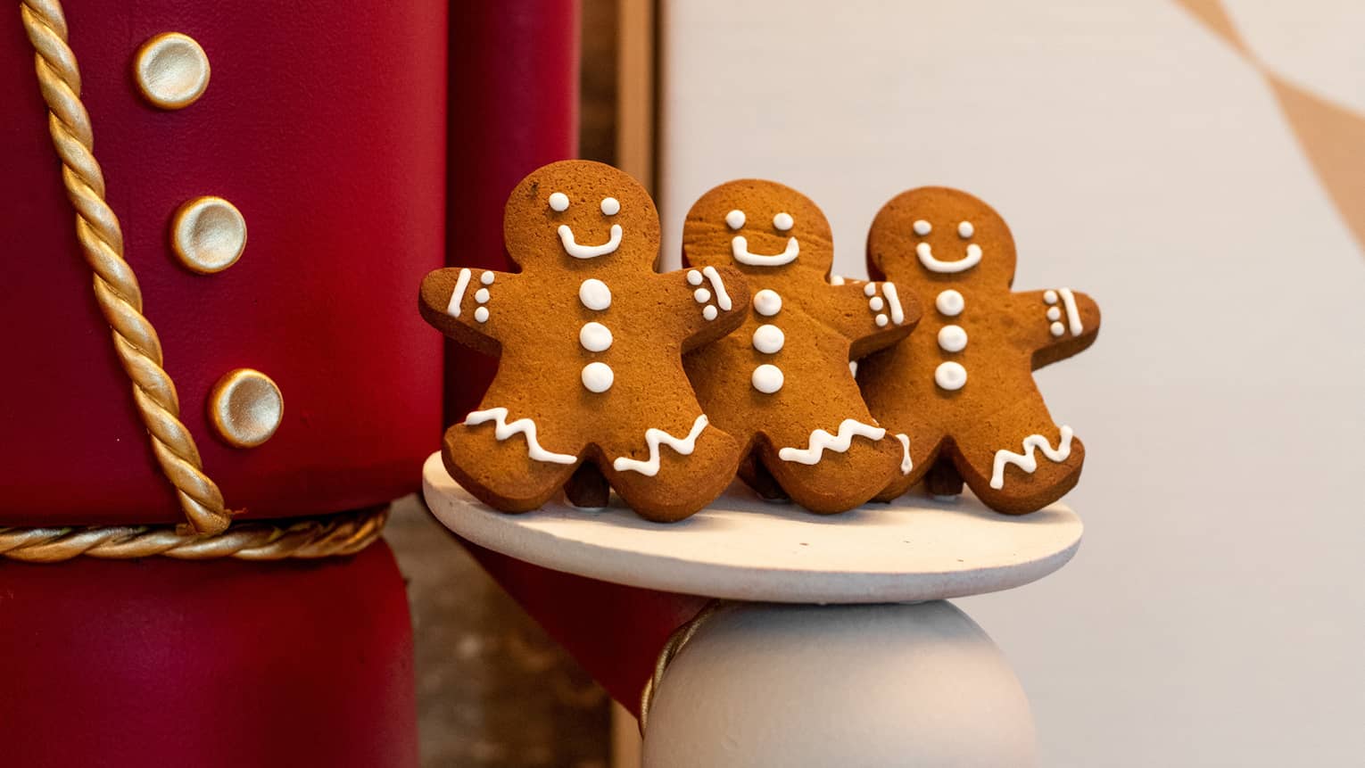 Gingerbread men cookies being held by a large nutcracker doll.