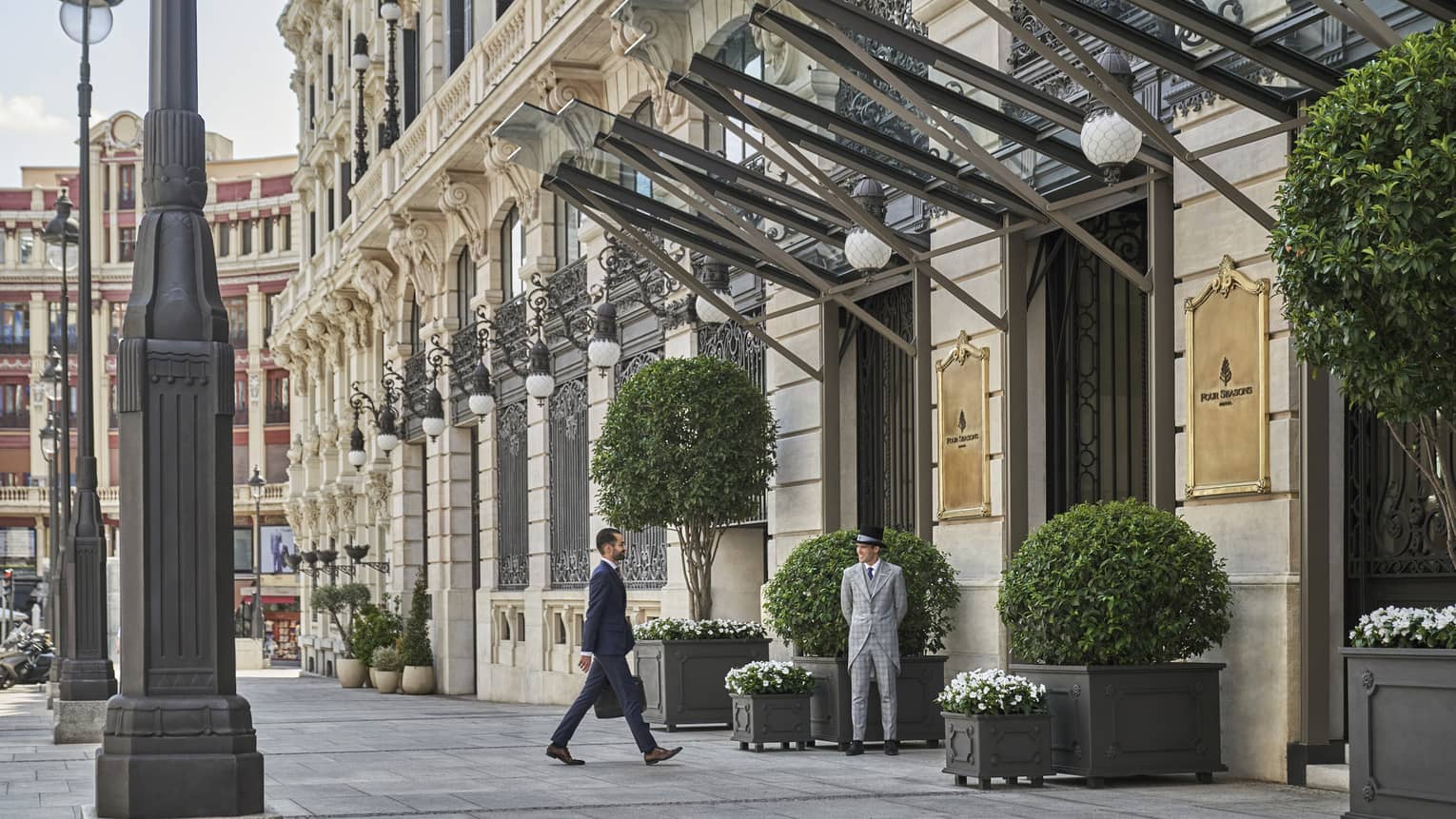 Person in suit carrying a briefcase and walking towards hotel entrance,Person in suit carrying a briefcase and walking towards hotel entrance