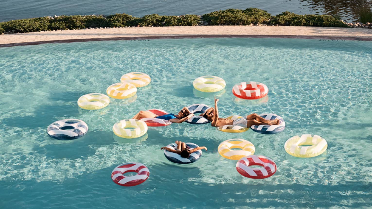Guests floating on floats in a pool.