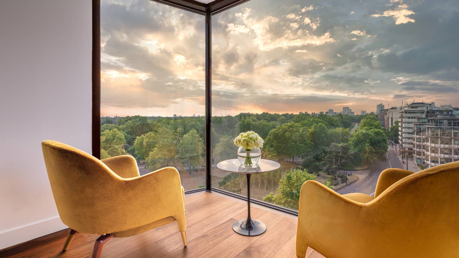 Two mustard-coloured club chairs and small round table on wood floor with views from large window