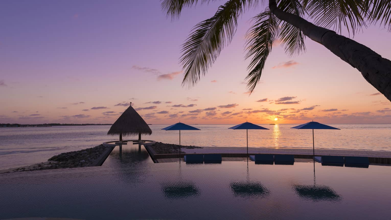 Sunset view of outdoor infinity pool near the beach 