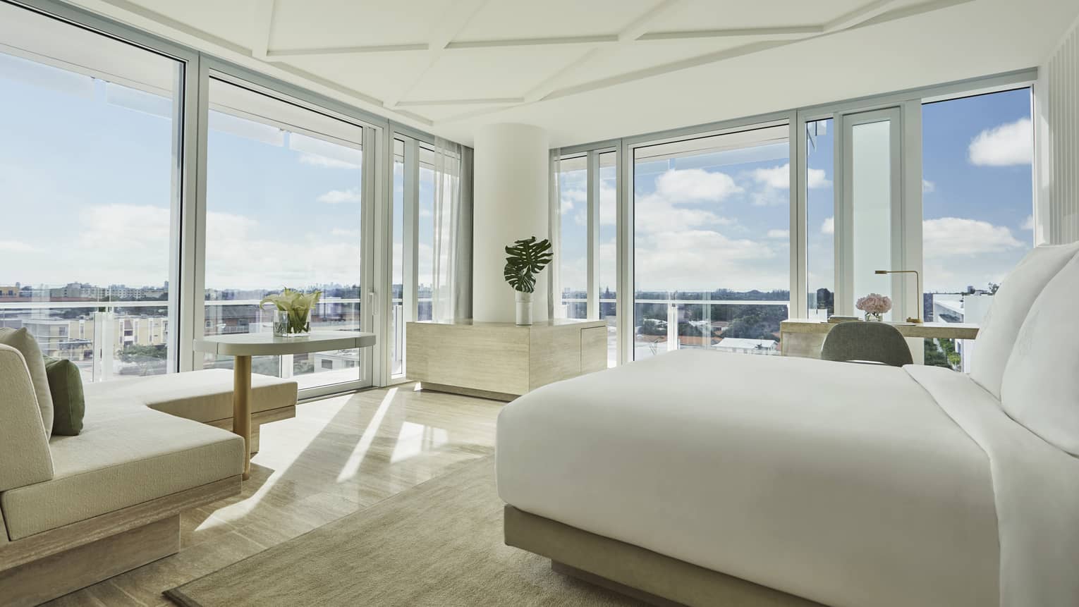 Sunset Studio Suite with modern white bed and chaise, and floor-to-ceiling windows with expansive views