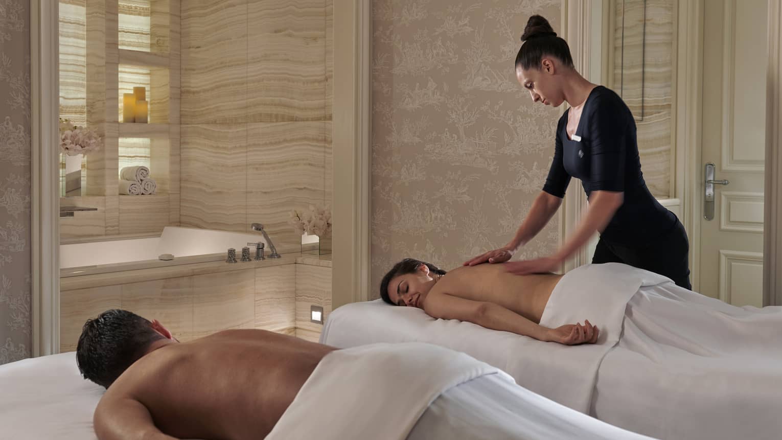 A four seasons staff massages a woman while her partner lies on a massage bet beside her at the four seasons george paris spa