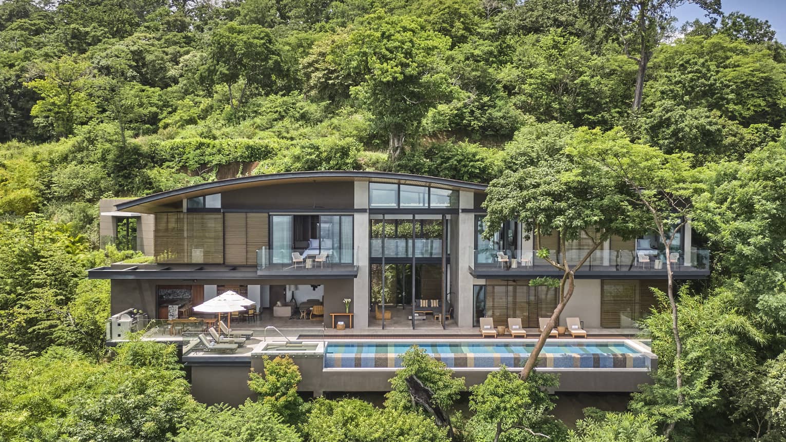 Exterior of private villa nestled in the trees with long rectangular pool