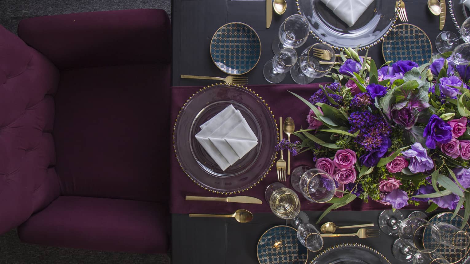 Aerial view of dining table with deep purple chair, table runner, flower arrangement