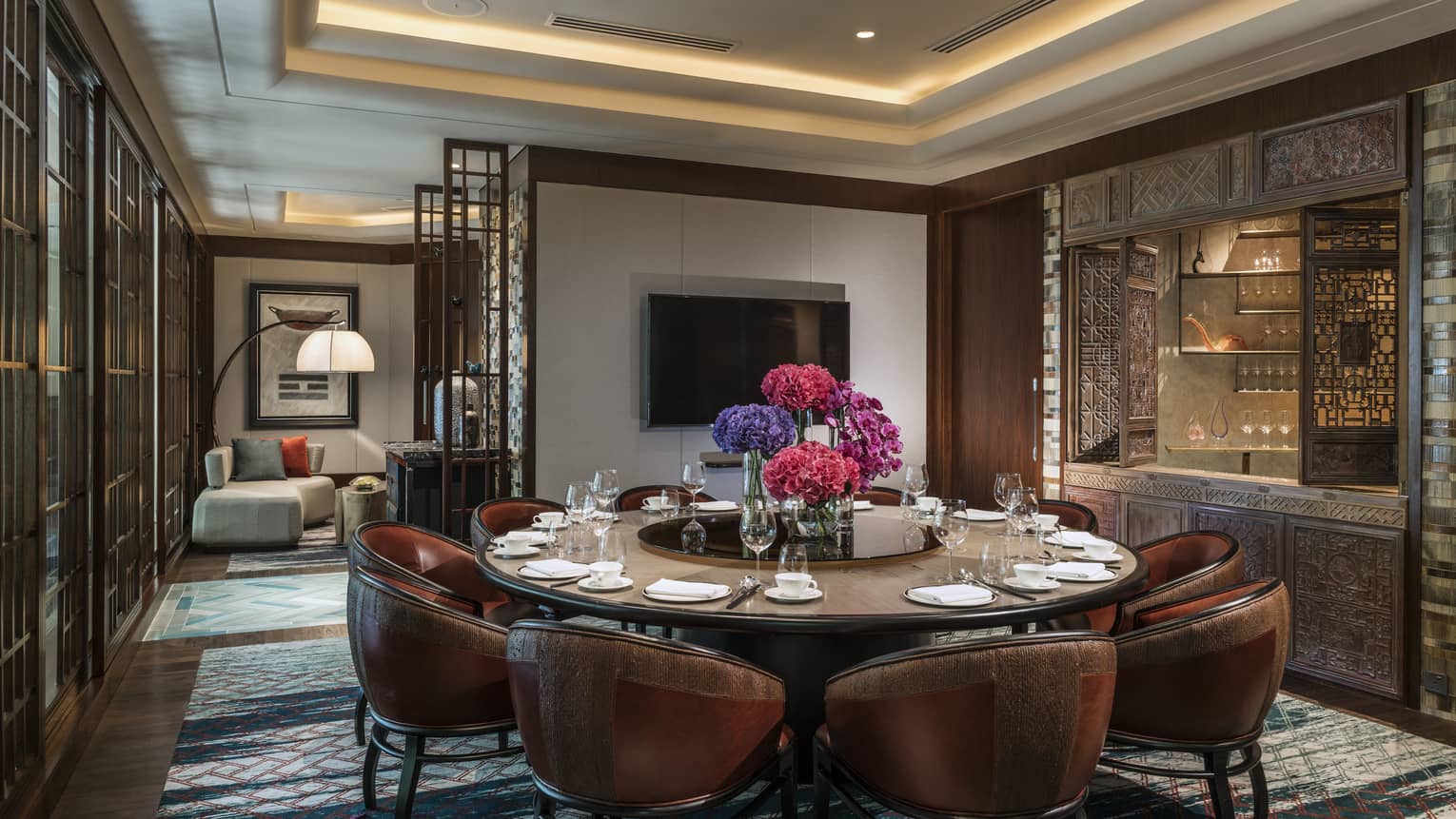 Leather bucket chairs around private meeting dining table, TV on wall