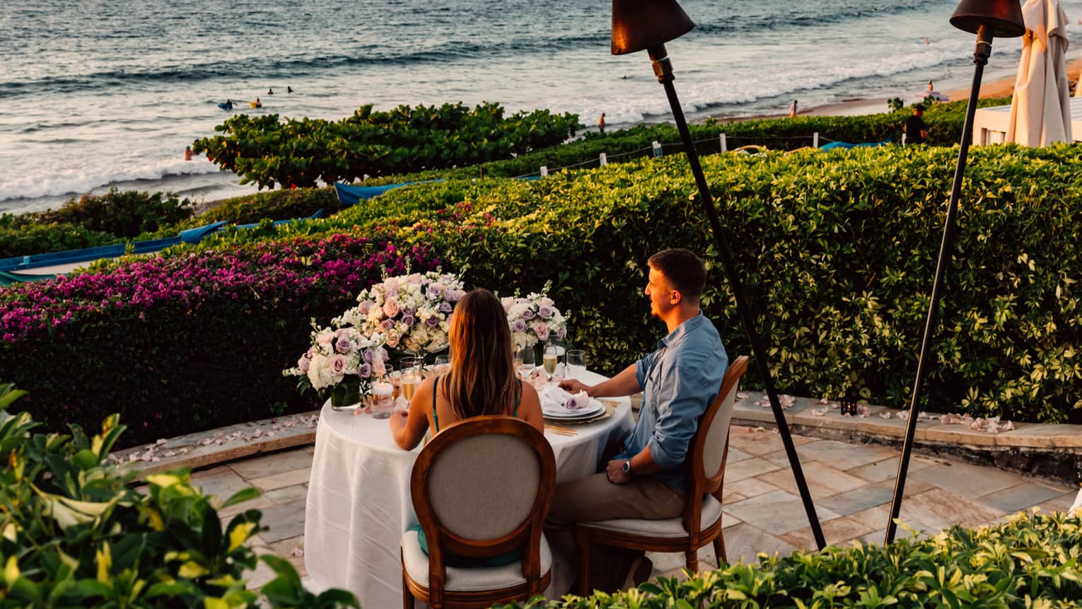 Man and woman dine at private round dining table outside near the ocean at Four Seasons Resort Maui