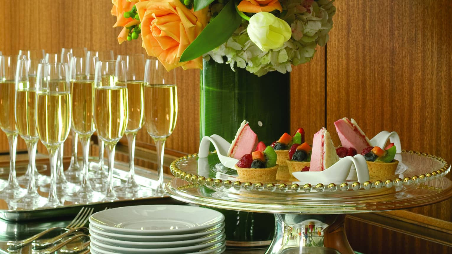 Intricate pastries, cakes and chocolates are arranged on a table next to a flower arrangement and champagne 