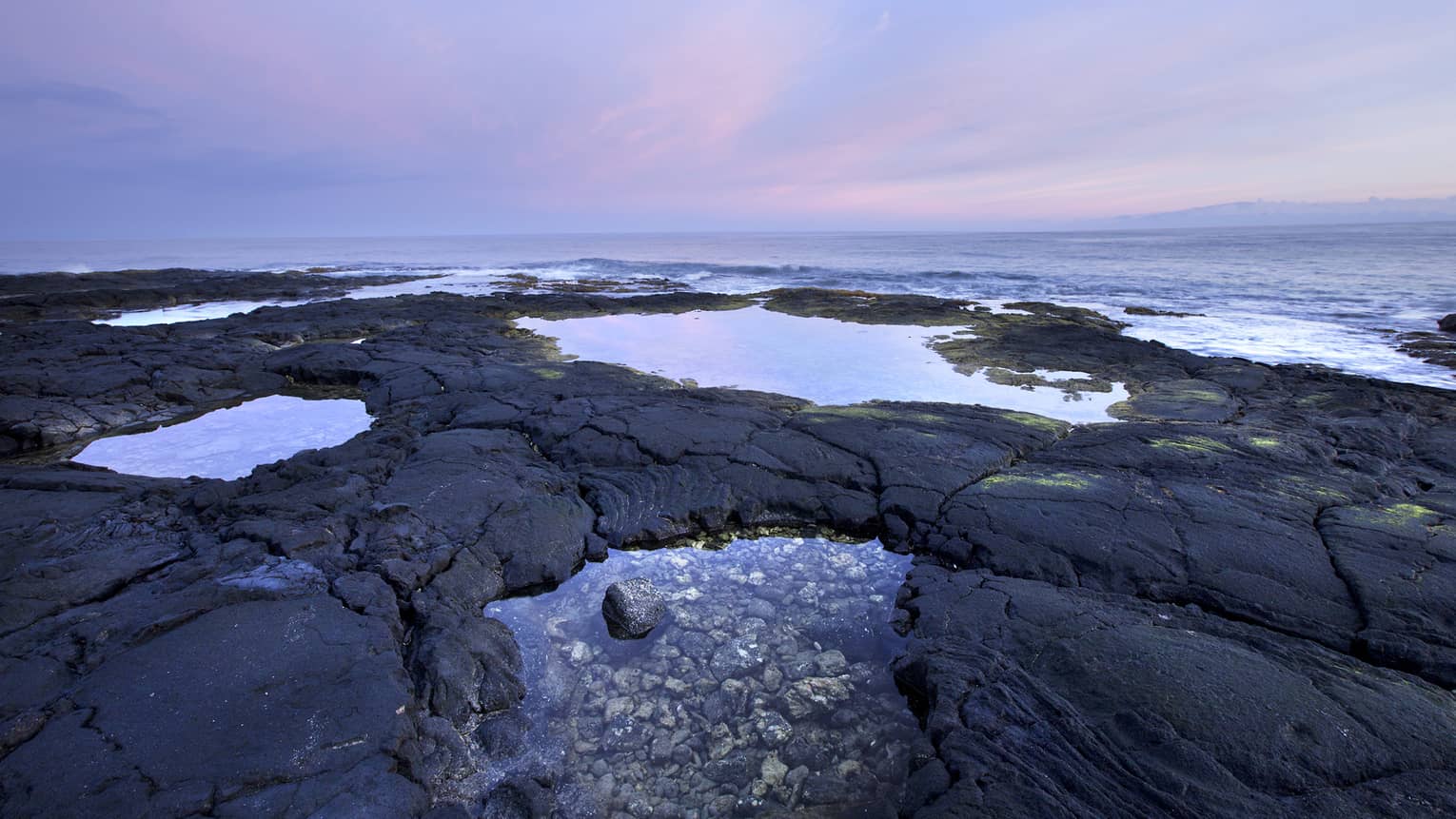 Pools of water on the Hualalai beach near sunset