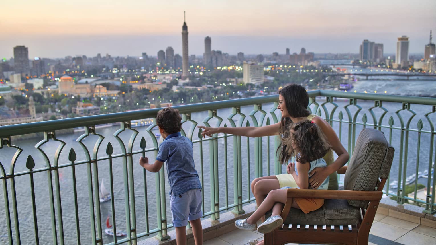 Woman seated with a young girl and beside a young boy standing, overlooking the Nile River and Cairo