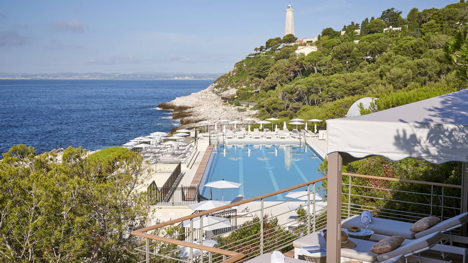 View from terrace of Club Dauphin pool, Mediterranean, green hillside and lighthouse