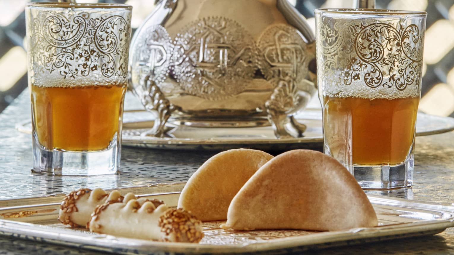 Pastries on tray in front of Moroccan tea glasses 