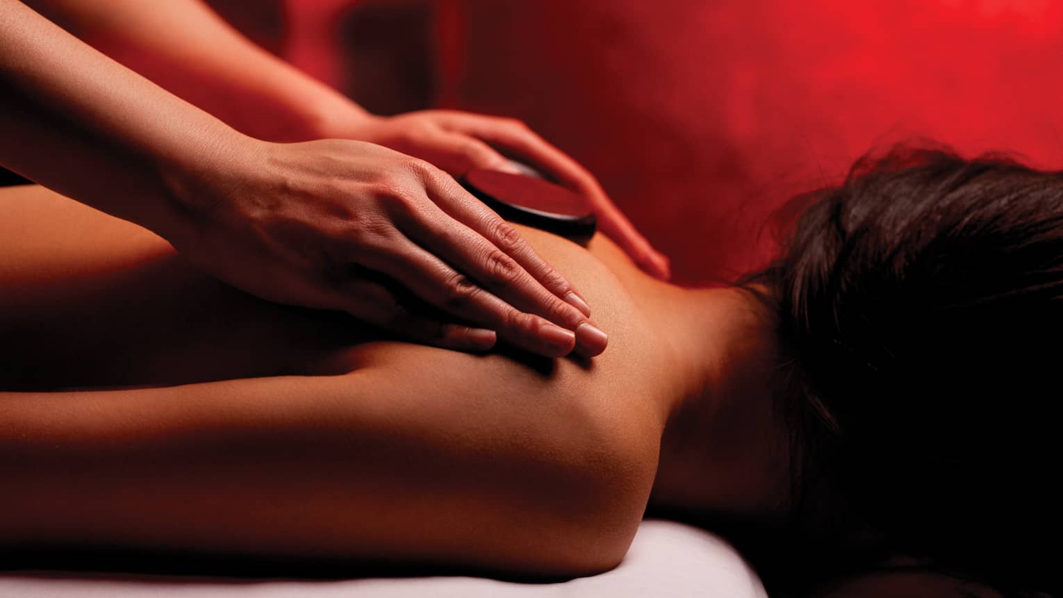 Hands rub woman's bare shoulders during Fusion Massage in spa