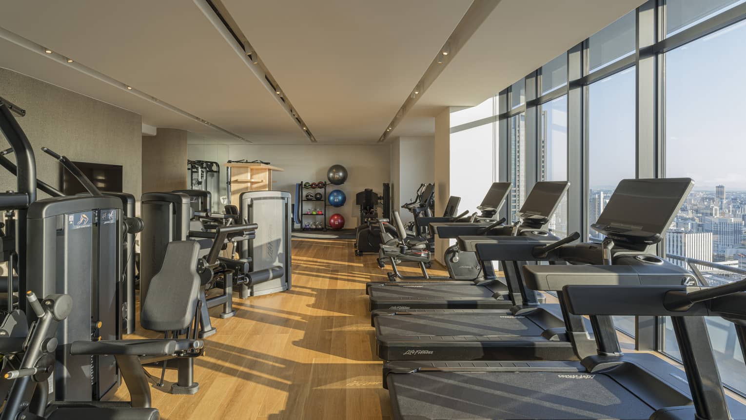 Indoor, light-filled gym at Four Seasons Hotel Suzhou, with a row of treadmills, bikes and other weight training machines