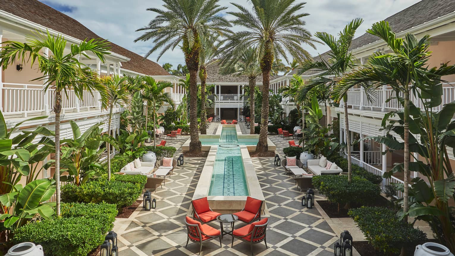 Patio chairs, tables around cross-shaped fountain, large palm trees in Hartford Courtyard