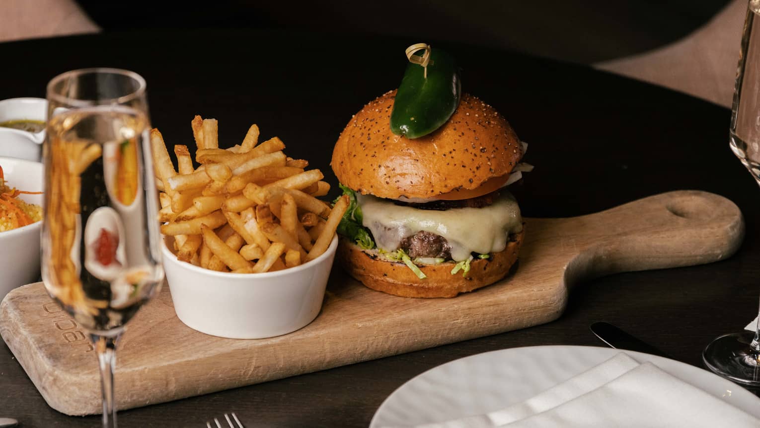 Craft burger and cup of fries on wooden serving board