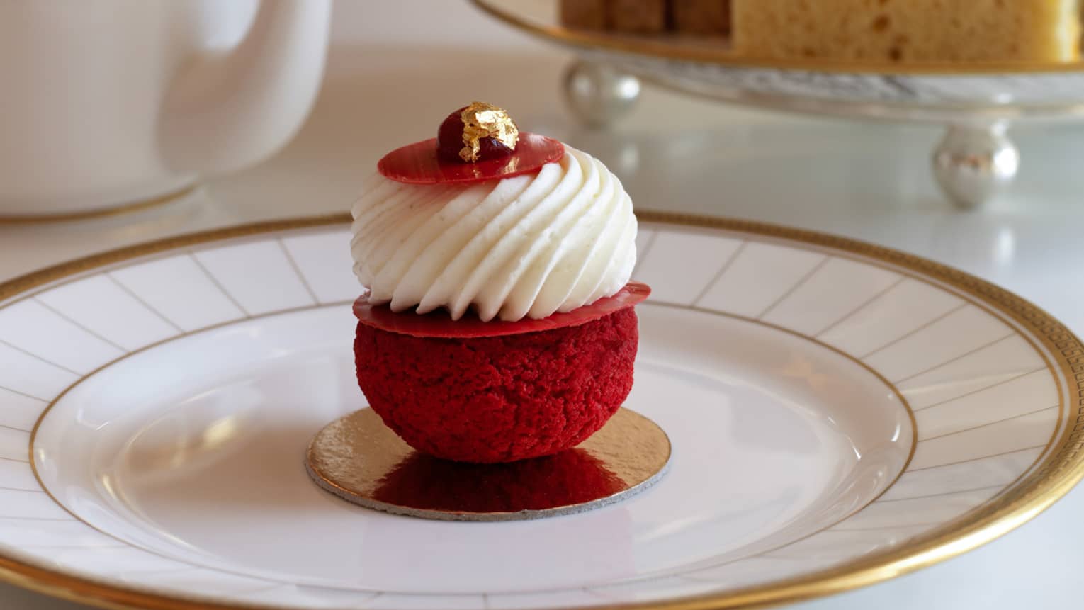 Afternoon tea at Rotunda Lounge serves red cream-topped pastry on white and gold plate