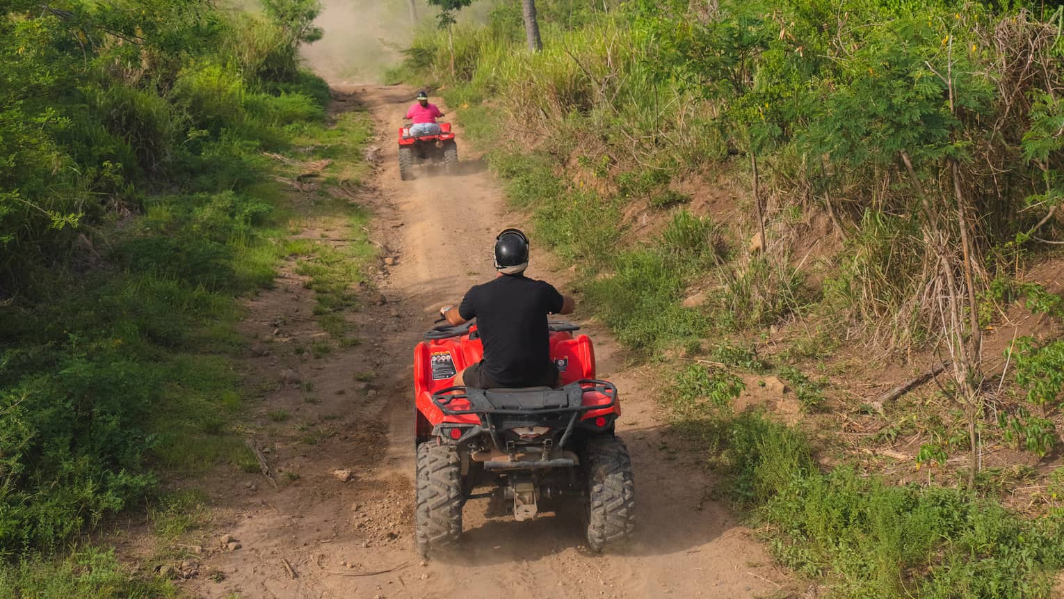 Off-road vehicles driving down a dirt path.