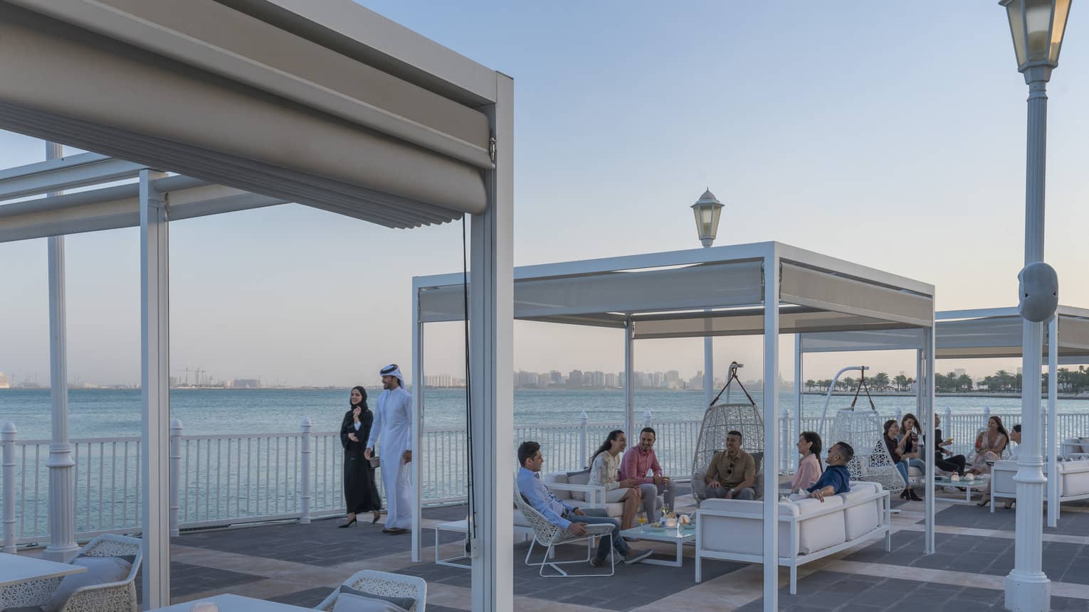 People mingle at outdoor lounge The Pier at Four Seasons Doha, overlooking the sea