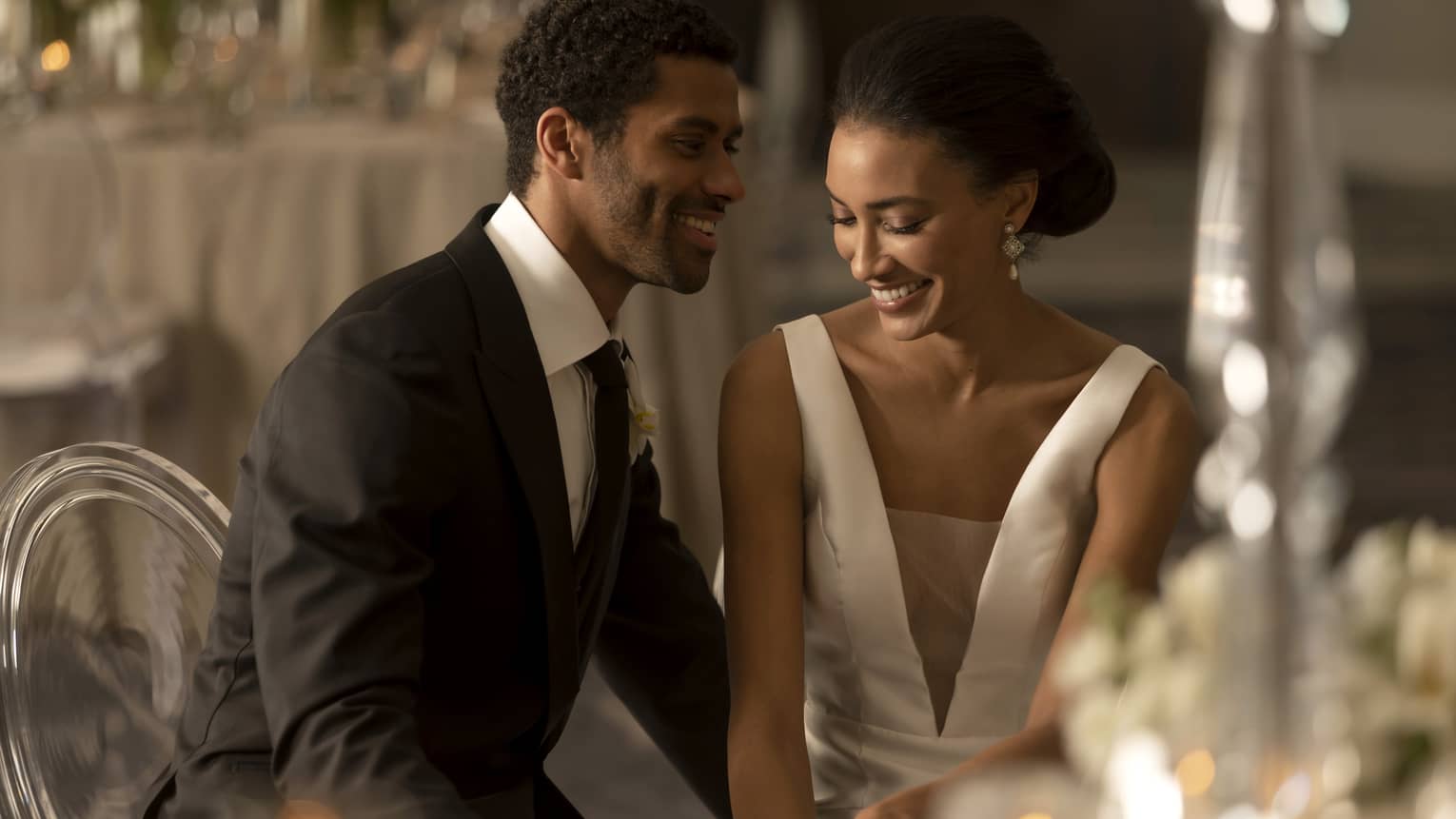 A bride and groom sitting at a table with candles.