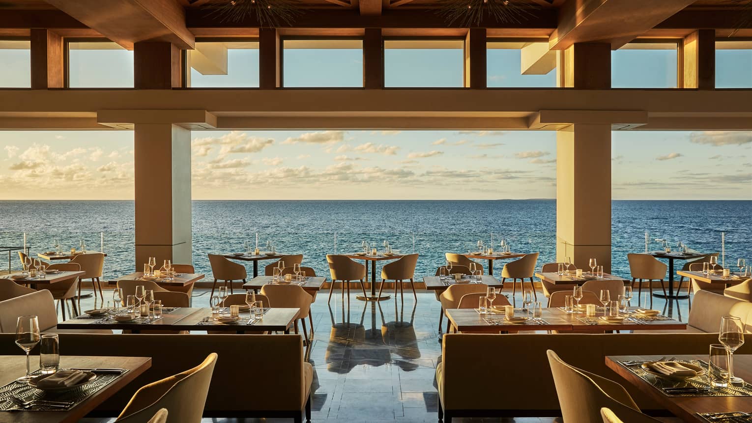 Elegant Coba open-air restaurant with dining tables and chairs, gleaming floors over open ocean