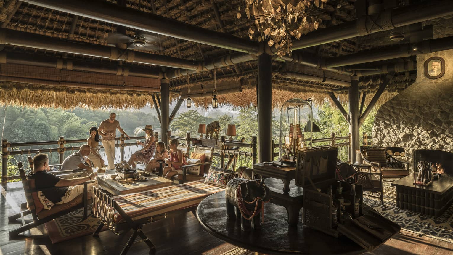 People hanging out at table in Burma Bar under thatched roof with water view