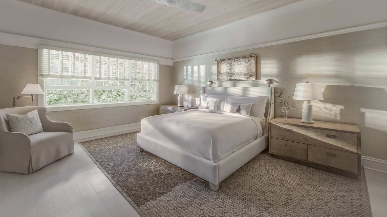 Sunlight and shadows shine through the window of a master suite bedroom