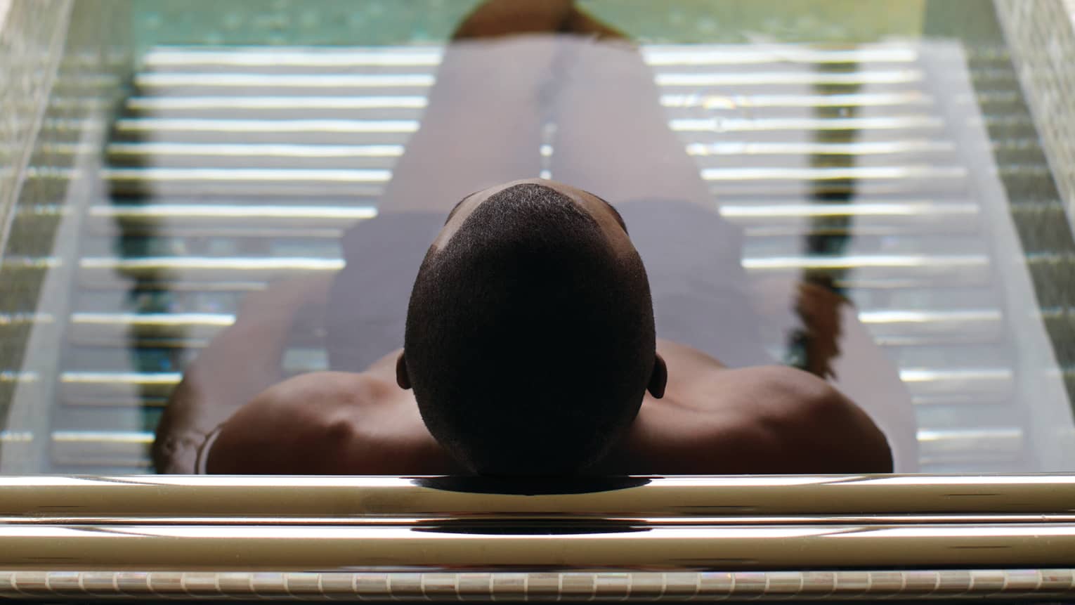 Silhouette of back of man's head, legs in spa tub