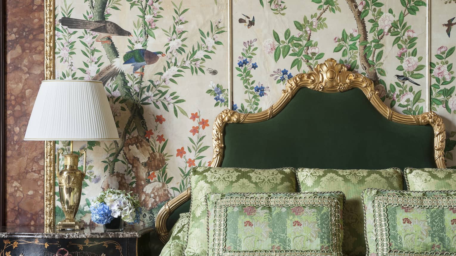 Bedroom with floral wall paper, gilded headboard and green silk bedding