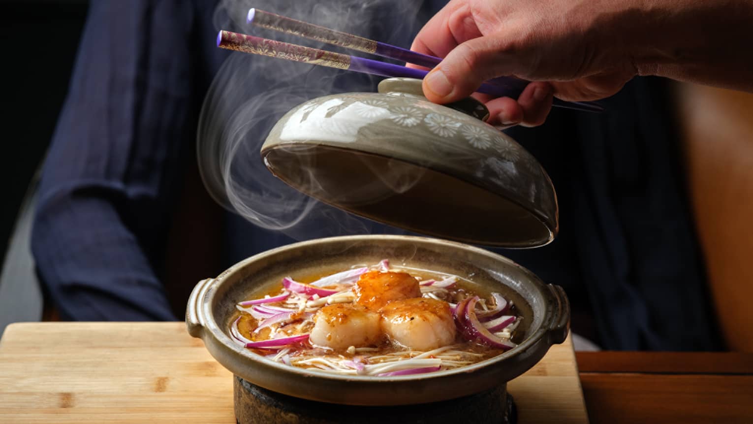 Scallops in a hote soup in a stone bowl.