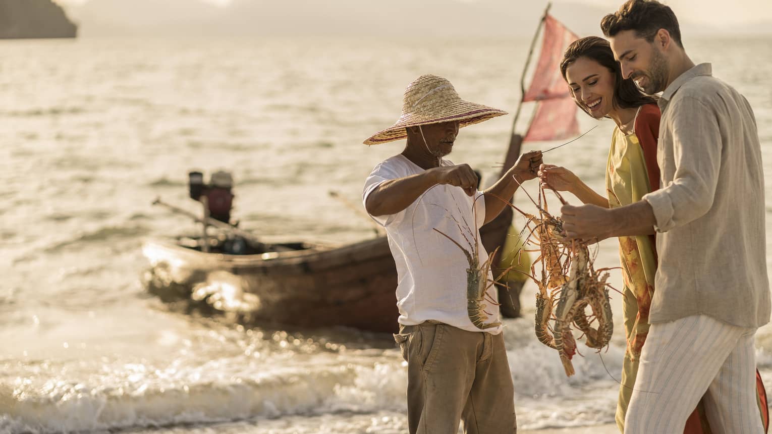 A four seaons fishing guide is holding and showing 4 lobsters to a man and a woman