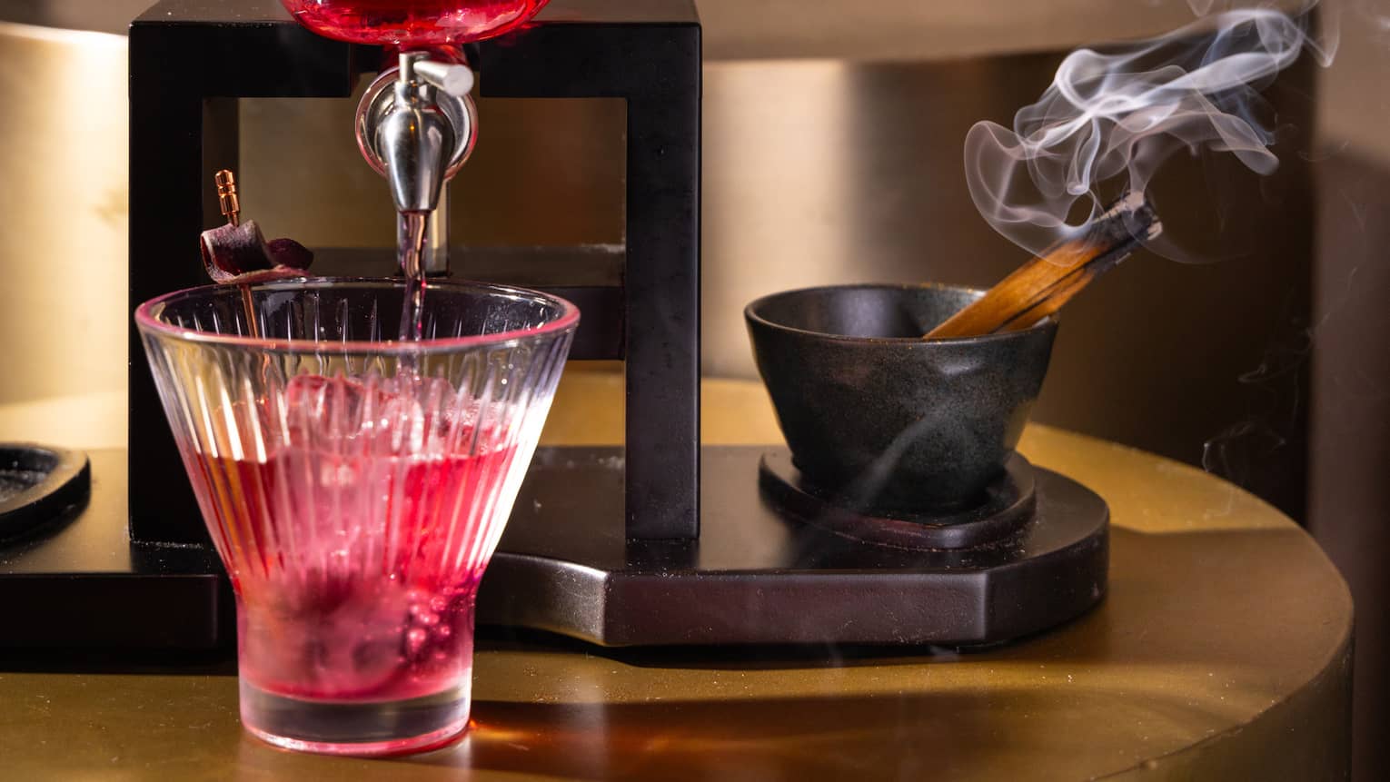 A red cocktail coming out a glass skull.