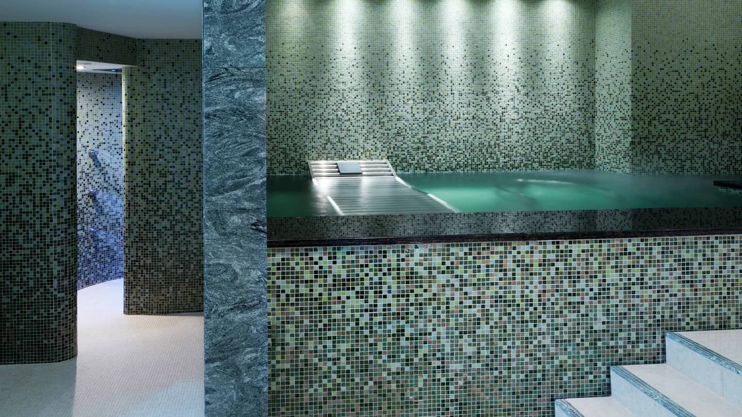 Raised bath with elaborate tile design in marble-and-tile spa room